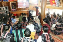 Des habitants de la commune frontalière d'A Vuong suivent la retransmission en direct de la séance d'ouverture du XIVe Congrès national du Parti à la maison Guol. Photo : VNA.