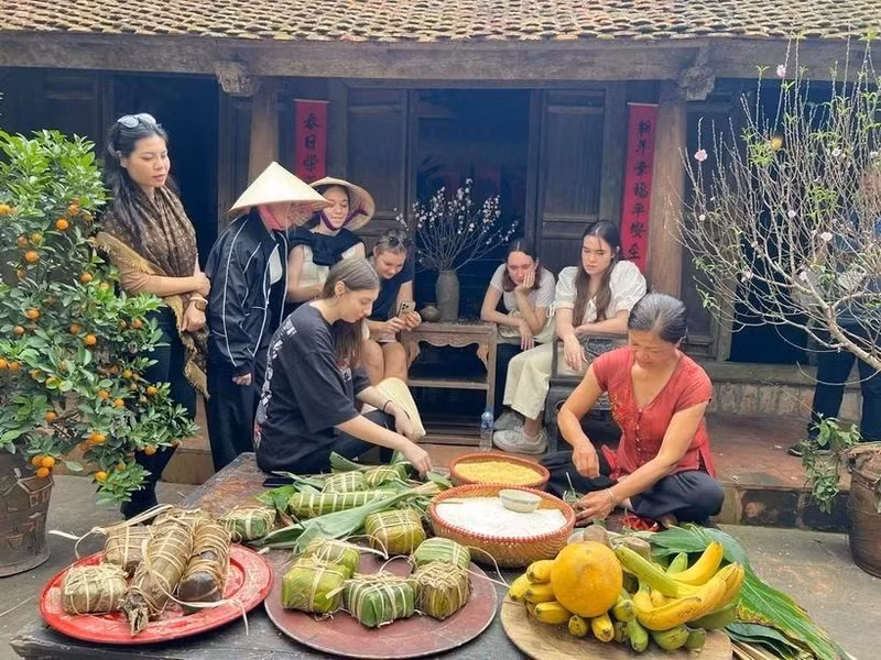 Des touristes étrangers essaient de confectionner des "banh chung" à l'ancien village de Duong Lam. Photo : VNA. 