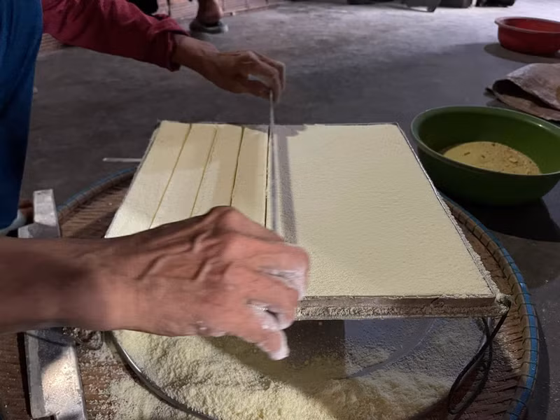 La farine de riz est ensuite pressée dans le moule pour former des petits biscuits de forme carrée.