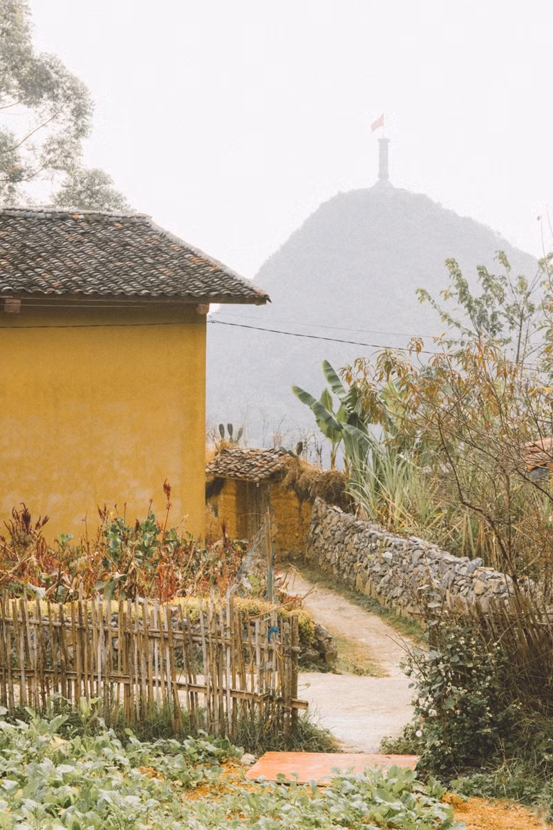 À l'entrée d'une maison locale, avec la tour du drapeau Lung Cu visible au loin. Chaque maison et chaque coin du village offrent des endroits parfaits pour la photographie.