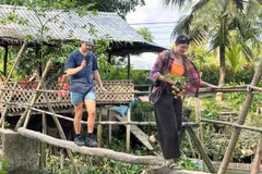 Des visiteurs découvrent l’expérience de la traversée d’un petit « pont suspendu », passerelle traditionnelle typique du delta du Mékong. Photo : SGGP.
