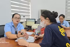 Des fonctionnaires du quartier de Mao Khe guident une citoyenne dans le dépôt en ligne de ses dossiers de certification sur le Portail national de la fonction publique. Photo : TTXVN