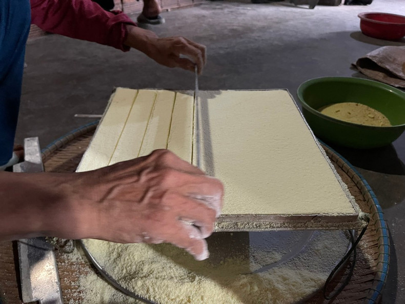 La farine de riz est ensuite pressée dans le moule pour former des petits biscuits de forme carrée. La farine de riz est ensuite pressée dans le moule pour former des petits biscuits de forme carrée.