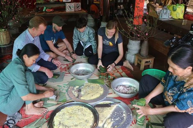 Des touristes mettent la main à la pâte pour confectionner des banh chung (gâteau de riz gluant de forme carrée) et banh tet (gâteau de riz gluant de forme cylindrique). Photo : VNA Des touristes mettent la main à la pâte pour confectionner des banh chung (gâteau de riz gluant de forme carrée) et banh tet (gâteau de riz gluant de forme cylindrique). Photo : VNA