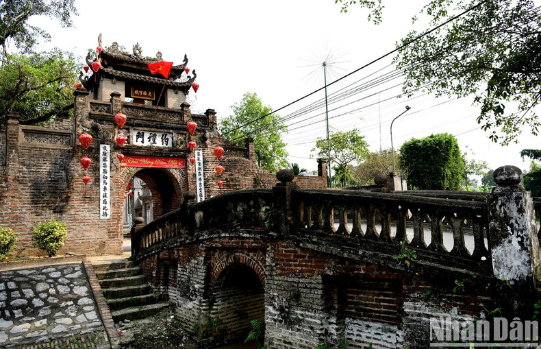 C’est par un pont arqué de deux mètres de large et de dix mètres de long que l’on entre dans le village. Précédemment, le fossé situé en dessous du pont est une tranchée profonde entourant tout le village, où étaient plantés des arbres de bambous. Cette tranchée servait de mur de protection contre les voleurs. Photo : The Duong /NDEL C’est par un pont arqué de deux mètres de large et de dix mètres de long que l’on entre dans le village. Précédemment, le fossé situé en dessous du pont est une tranchée profonde entourant tout le village, où étaient plantés des arbres de bambous. Cette tranchée servait de mur de protection contre les voleurs. Photo : The Duong /NDEL