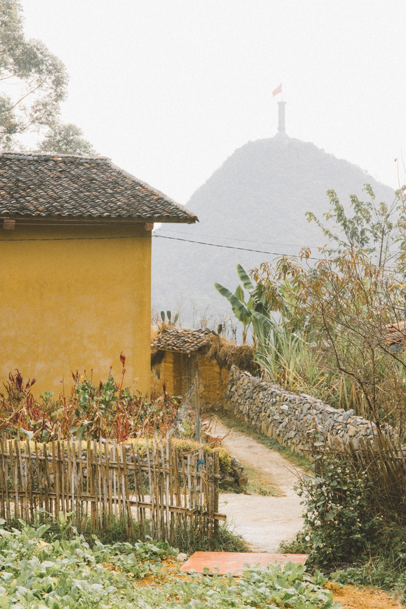 À l'entrée d'une maison locale, avec la tour du drapeau Lung Cu visible au loin. Chaque maison et chaque coin du village offrent des endroits parfaits pour la photographie.