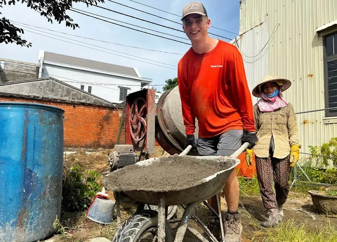 Un jeune volontaire américain, tout sourire, pousse une brouette. Photo : thoidai.com.vn 4.jpg
