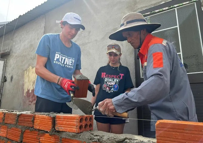Un maçon de la commune de Van Tuong montre à des élèves américains comment aligner les briques pour construire un mur. Photo : thoidai.com.vn 2.jpg