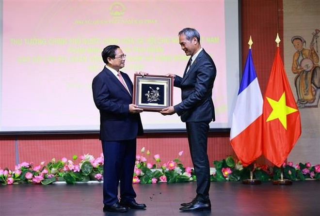 Le Premier ministre Pham Minh Chinh (à gauche) offre un cadeau à un représentant de la communauté vietnamienne en France. Photo : VNA. tang-qua.jpg