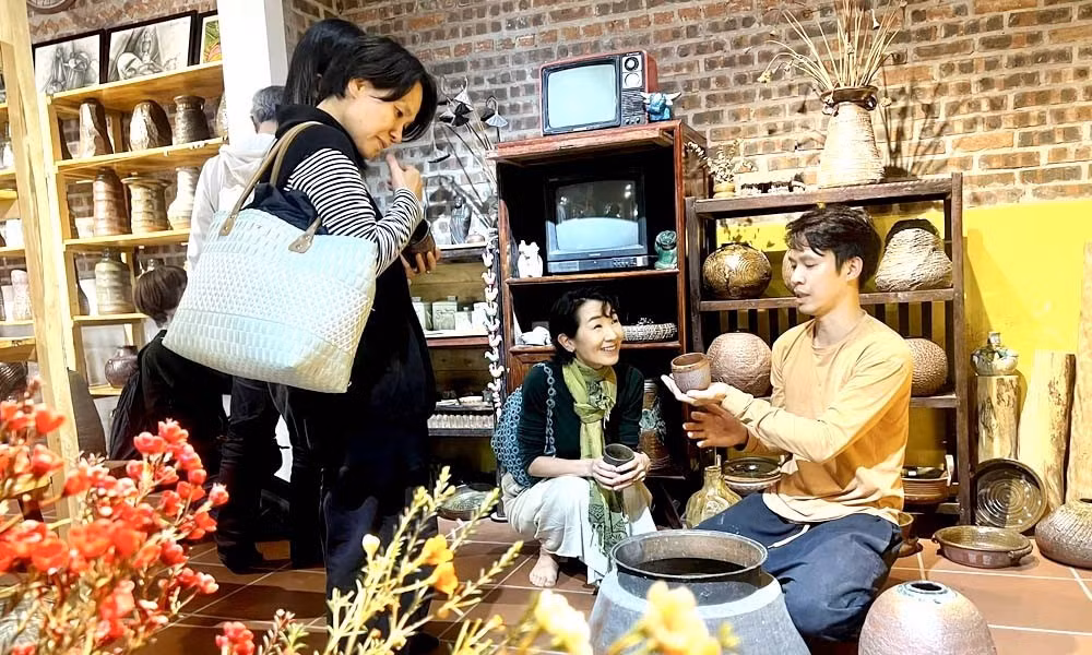 Le jeune artisan Bui Van Huan présente des pièces uniques de céramique artisanale à des visiteurs internationaux. Photo: langngheviet.com.vn