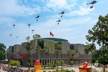 Une formation de dix hélicoptères arborant le drapeau du Parti et le drapeau national survolent la place Ba Dinh. Photo : Giang Huy.