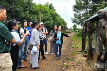 Les visiteurs découvrent et expérimentent les maisons funéraires ainsi que les statues funéraires du peuple Jrai. Photo : nhandan.vn