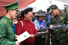 Les cadres et soldats distribuent des documents juridiques et assurent la sensibilisation auprès des habitants au marché. Photo : qdnd.vn