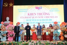 La vice-ambassadrice de la République démocratique populaire lao au Vietnam, Lattana Sihalat (cinquième en partant de la gauche), remet des certificats de mérite aux collectifs et aux familles exemplaires pour leur engagement à accueillir des étudiants laotiens comme enfants adoptifs. Photo : thoidai.com.vn