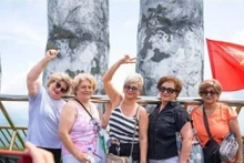Les touristes étrangers apprécient de se prendre en photo sur le pont d’Or, orné de drapeaux vietnamiens éclatants, dans la zone touristique. Photo : baoquocte.vn