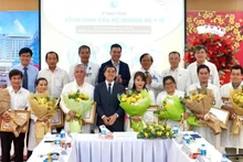 Le vice-ministre de la Santé, Tran Van Thuan, offre des fleurs et un certificat de mérite à l’équipe qui réalise une intervention fœtale sur une patiente singapourienne. Photo : nhandan.vn