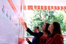 Des électeurs se rendent à un bureau de vote local pour consulter la liste des candidats à la 16e Assemblée nationale et aux conseils populaires à tous les niveaux pour le mandat 2026-2031. Photo : VNA 