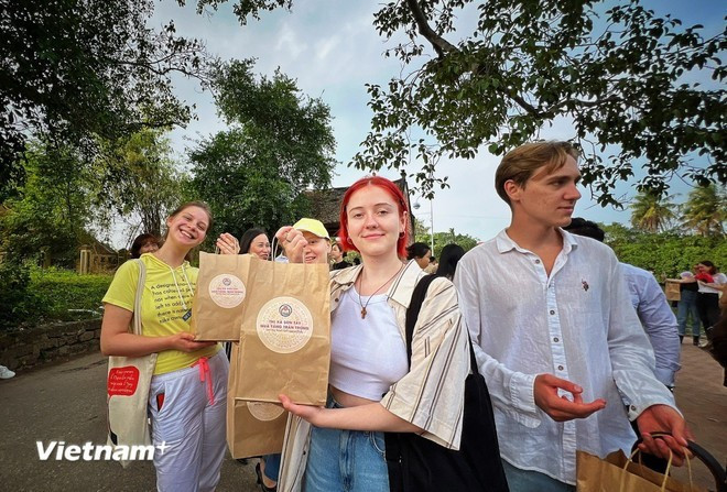 Des touristes étrangers reçoivent des cadeaux après avoir visité l'ancien village de Duonng Lam. Photo: Vietnam+