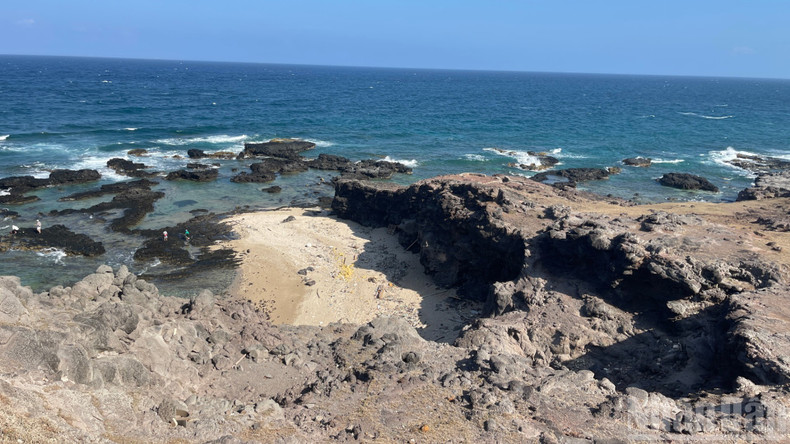 Des visiteurs descendent au bord de la mer pour prendre des photos.