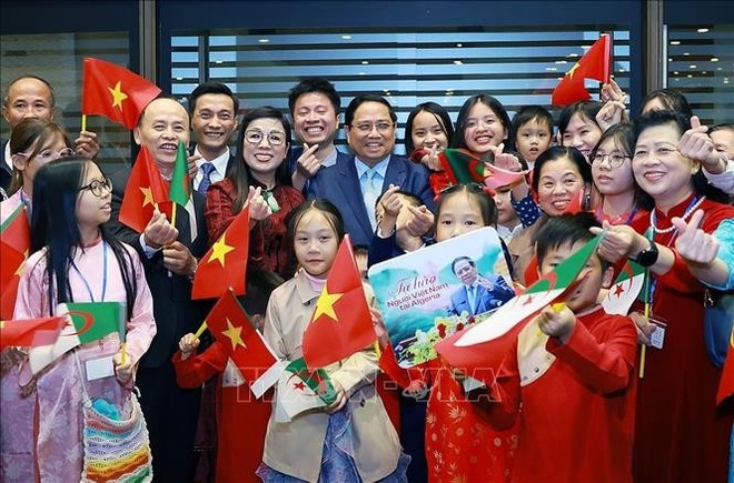 Le Premier ministre Pham Minh Chinh et son épouse prennent une photo avec des représentants de la communauté vietnamienne en Algérie. Photo: VNA