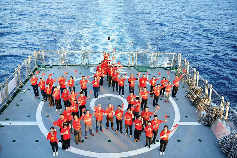 Des membres de la diaspora forment une étoile dorée à cinq branches sur le pont du navire KN390 lors d’une mission dans l’archipel de Truong Sa. Photo : Hong Chau. b.png