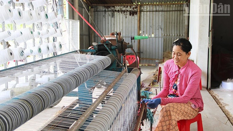 Mme Nguyen Thi Minh Trang, propriétaire d’un atelier de tissage de nattes à Duc My, commune de Nhi Long, est en train de tisser une natte à l’aide d’un métier semi-automatique. 2.jpg