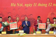 Le PM vietnamien Nguyên Xuân Phuc (au centre) félicite les sélections nationales de football masculine et féminine. Photo : NDEL.