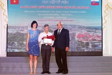 L’ambassadrice par intérim de Slovaquie au Vietnam, Ivana Belcáková, offre un bouquet de fleurs à Trân Xuân Dam, l’un des rédacteurs du Dictionnaire tchèque-vietnamien. Photo : VNA.