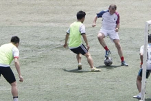L’ambassadeur de France (maillot tricolore) joue au football.