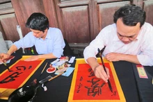 Les lettrés calligraphes écrivent les idéogrammes chinois sur les papiers pourpres avec la plume et l'encre de Chine. Photo: Minh Hanh/NDEL.