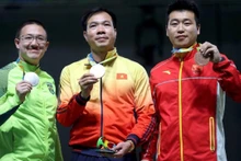 Hoàng Xuân Vinh (au milieu) avec sa médaille d’or historique. Photo: Reuters.