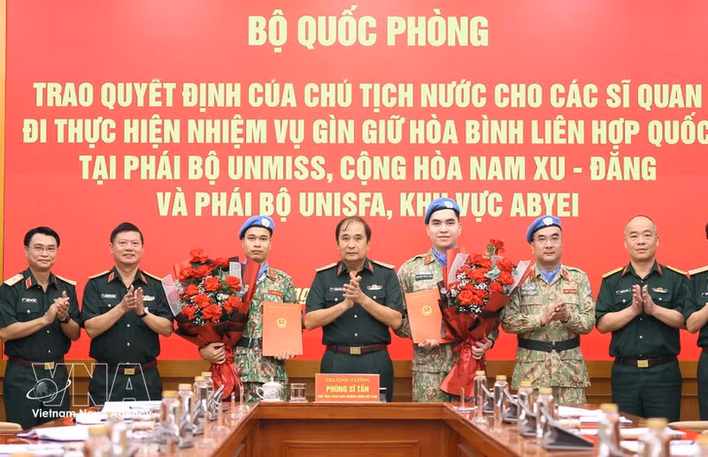 Le général de corps d’armée Phung Si Tan (au milieu) remet la décision à deux officiers de l’Armée populaire du Vietnam. Photo : VNA.