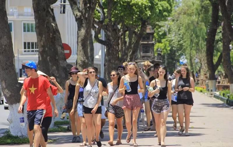 Des touristes étrangers sous un soleil ardent à Hanoi. Photo : VTC News.
