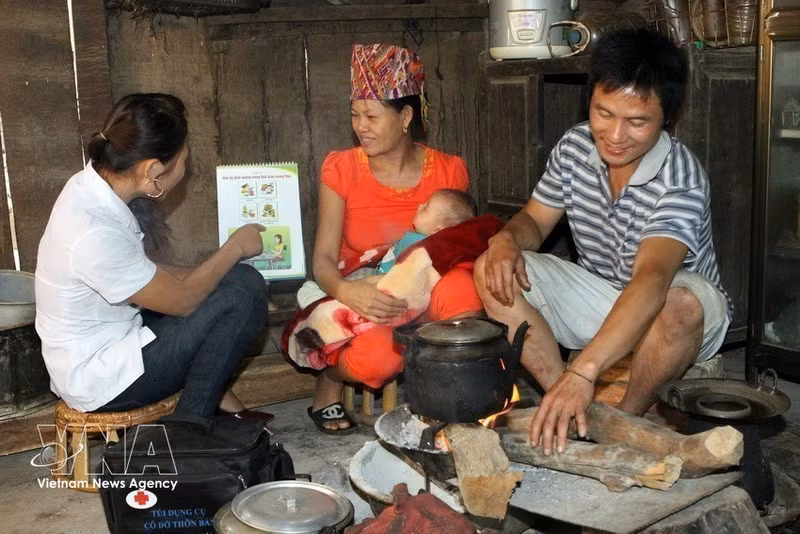 Un agent de santé communautaire guide une mère dans les soins à prodiguer à son nouveau-né province de Nghe An. Photo : VNA.