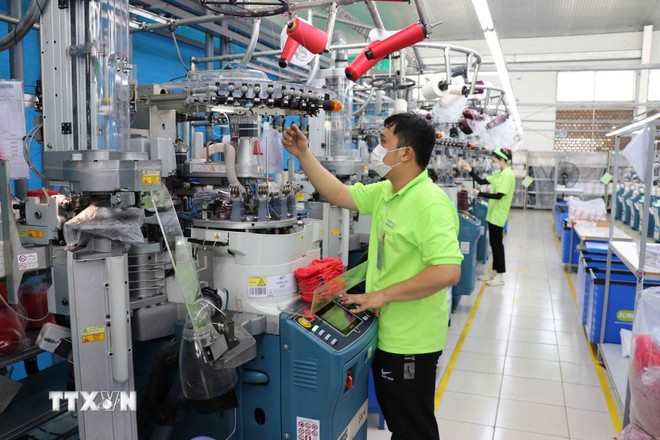 Un ouvrier de l'usine Sung Hwa Vina (capitale sud-coréenne) dans le parc industriel de Hoa Binh (Tay Ninh) vérifie le fil sur une machine à tisser des chaussettes. Photo : VNA. 0808-viet-nam-han-quoc-33.jpg