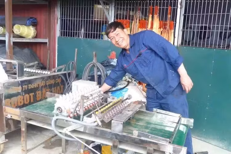 Pham Van Hat pose aux côtés de son célèbre produit, le "robot semeur". Photo : sggp.org.vn