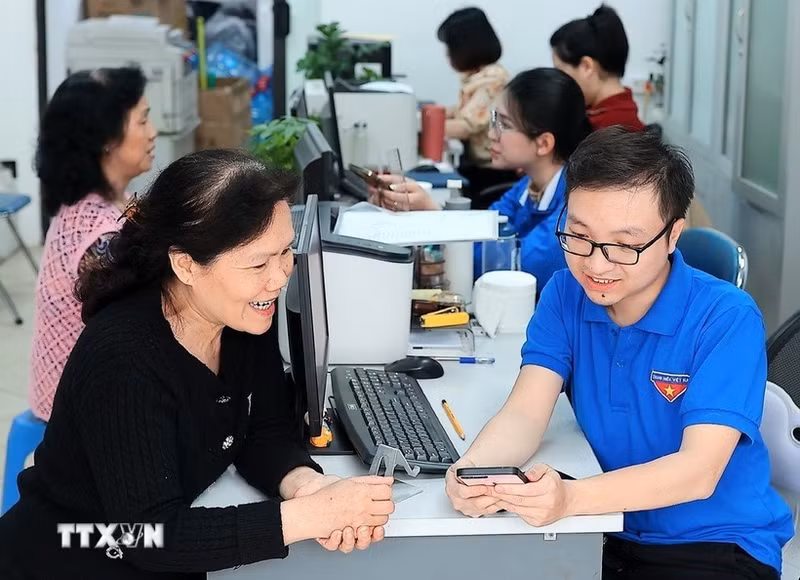 Des jeunes volontaires de Hàng Bồ (Hanoï) aident les habitants dans les démarches administratives en ligne. Photo : VNA.