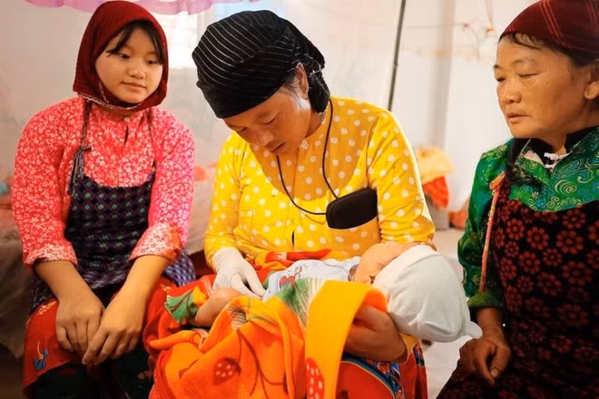 Une sage-femme prend un bébé dans ses bras sous le regard attentif de sa mère. Photo : VNA