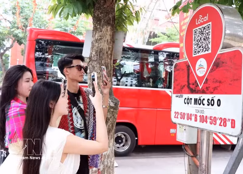 Les touristes scannent le code QR au km 0 à Ha Giang pour obtenir des informations touristiques. Photo: VNA