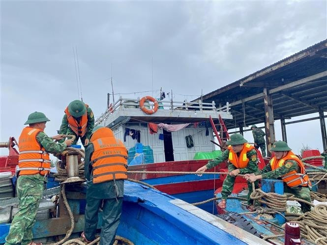 Des gardes-frontières aident des pêcheurs à consolider et à amarrer leurs bateaux. Photo : VNA.