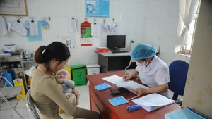 Le personnel médical examine et vérifie l'état de santé de l'enfant avant la vaccination. Photo : VNA.