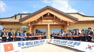 Les délégués sud-coréens et vietnamiens signent des tuiles à contruire le toit de la Maison communautaire de Bonghwa. Photo : VNA.