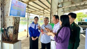 Des pêcheurs scannent le code QR au port de Tiên Châu. Photo : nhandan.vn