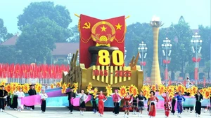 Un véhicule miniature portant l'emblème national de la République socialiste du Vietnam mène le défilé militaire et le cortège de masse. Photo : VNA.