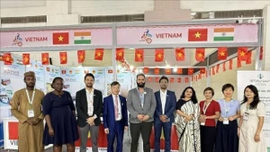 Le conseiller commercial Bùi Trung Thuong (4e de gauche à droite) et des invités nationaux et étrangers visitant le stand. Photo: VNA