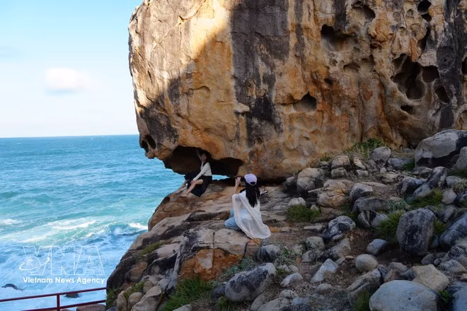 Des touristes immortalisent leur passage devant un rocher aux formes singulières à Hang Rai. Photo : VNA.