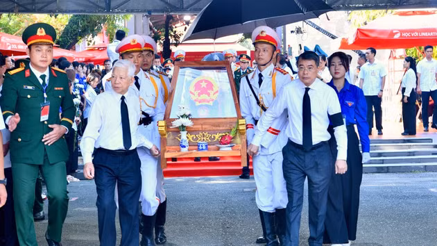 Le PM Le Minh Hung (à droite), l’ancien président Nguyen Minh Triet (à gauche) et d’autres délégués escortent les dépouilles des martyrs depuis le parc Le Thi Rieng. Photo : NDEL.
