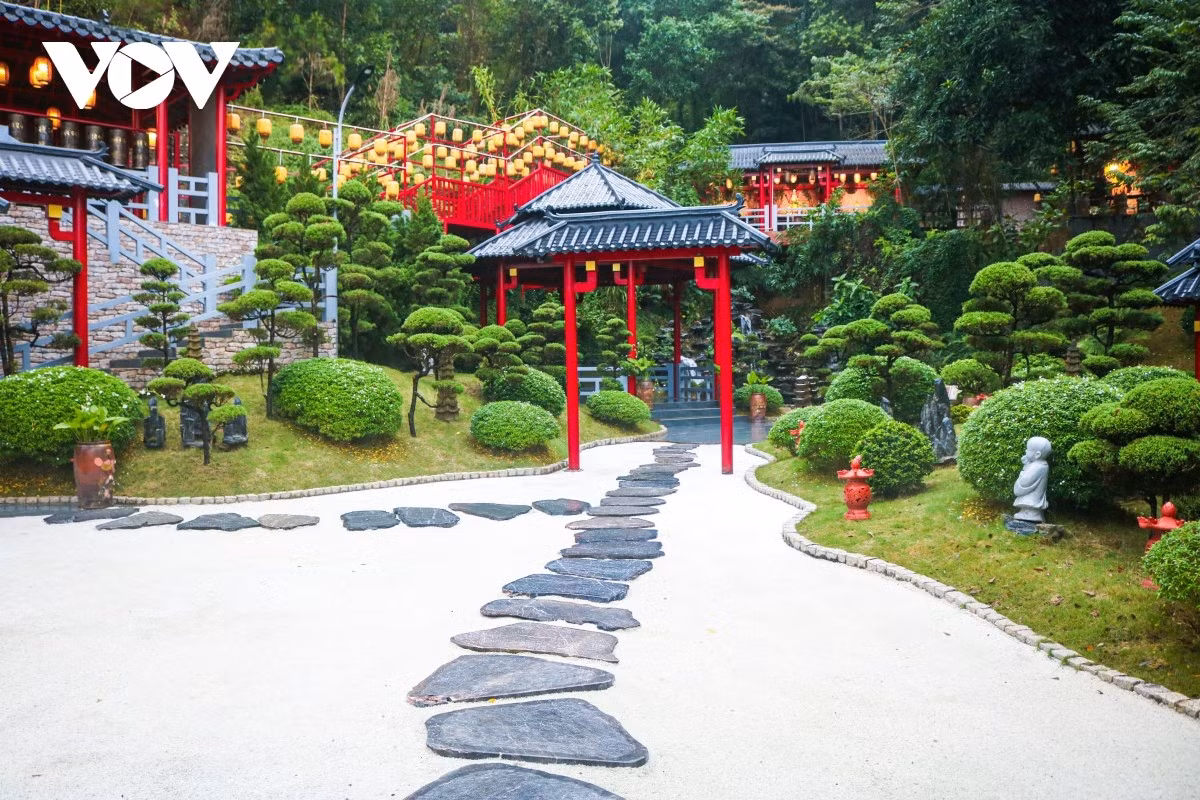 L’allée menant au temple est couverte de graviers blancs, entourée de collines plantées d’herbe japonaise et de pins.