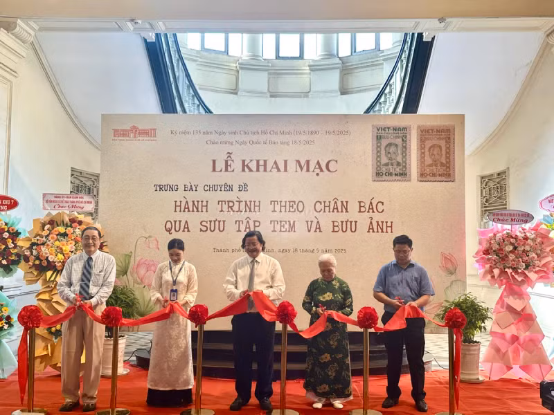 Des délégués coupent le ruban inaugural de l'exposition thématique "Sur les traces de l'Oncle Hô à travers une collection de timbres et de cartes postales". 