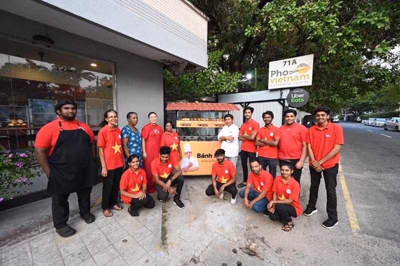 Des personnels du restaurant vietnamien Pho à côté de la charrette à pain. Photo : baoquocte.vn